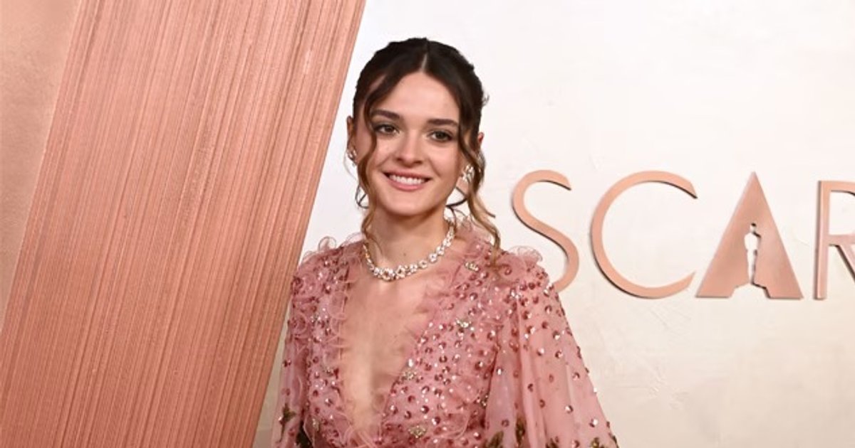 Charlotte Lawrence in rosa Kleid mit goldener Stickerei und Kätzchentaschendetai | Cinexcepción